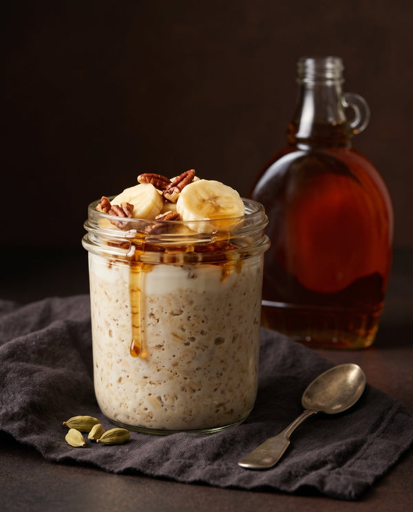 Cardamom maple overnight oats in a glass jar topped with banana and pecans